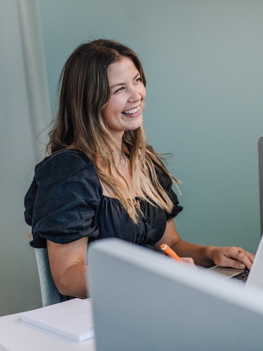 Sharp & Carter Specialist Recruitment, Our Method, Female Worker Smiling at Desk