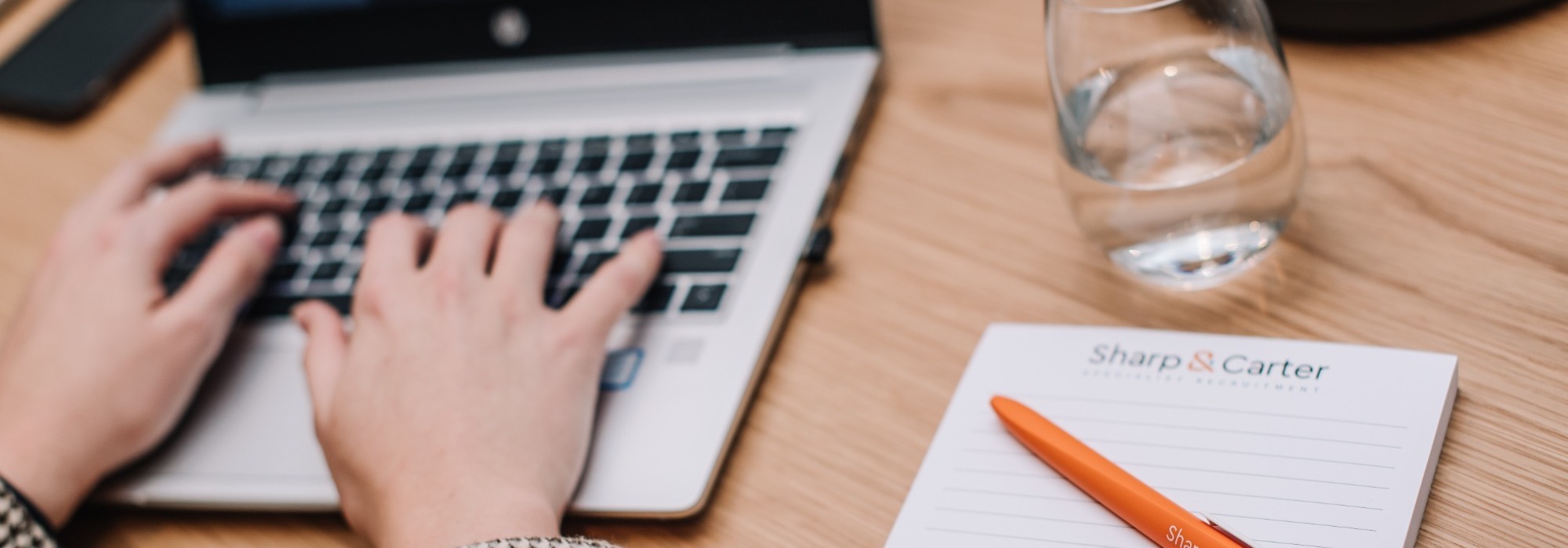 Sharp & Carter Specialist Recruitment, News & Insights, Working on Laptop with Notepad
